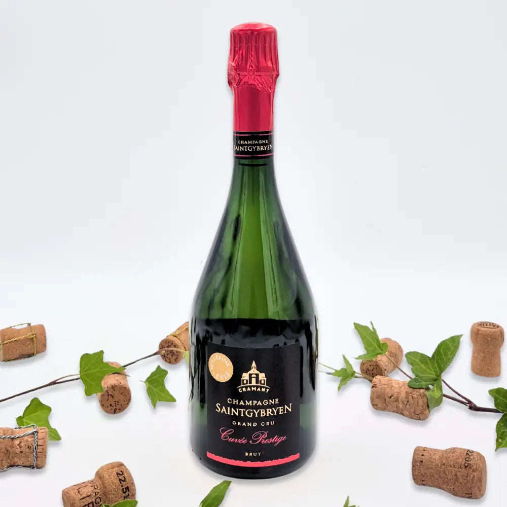 Cuvée Prestige omgivet af vinkorker, grønne blade på hvid baggrund.