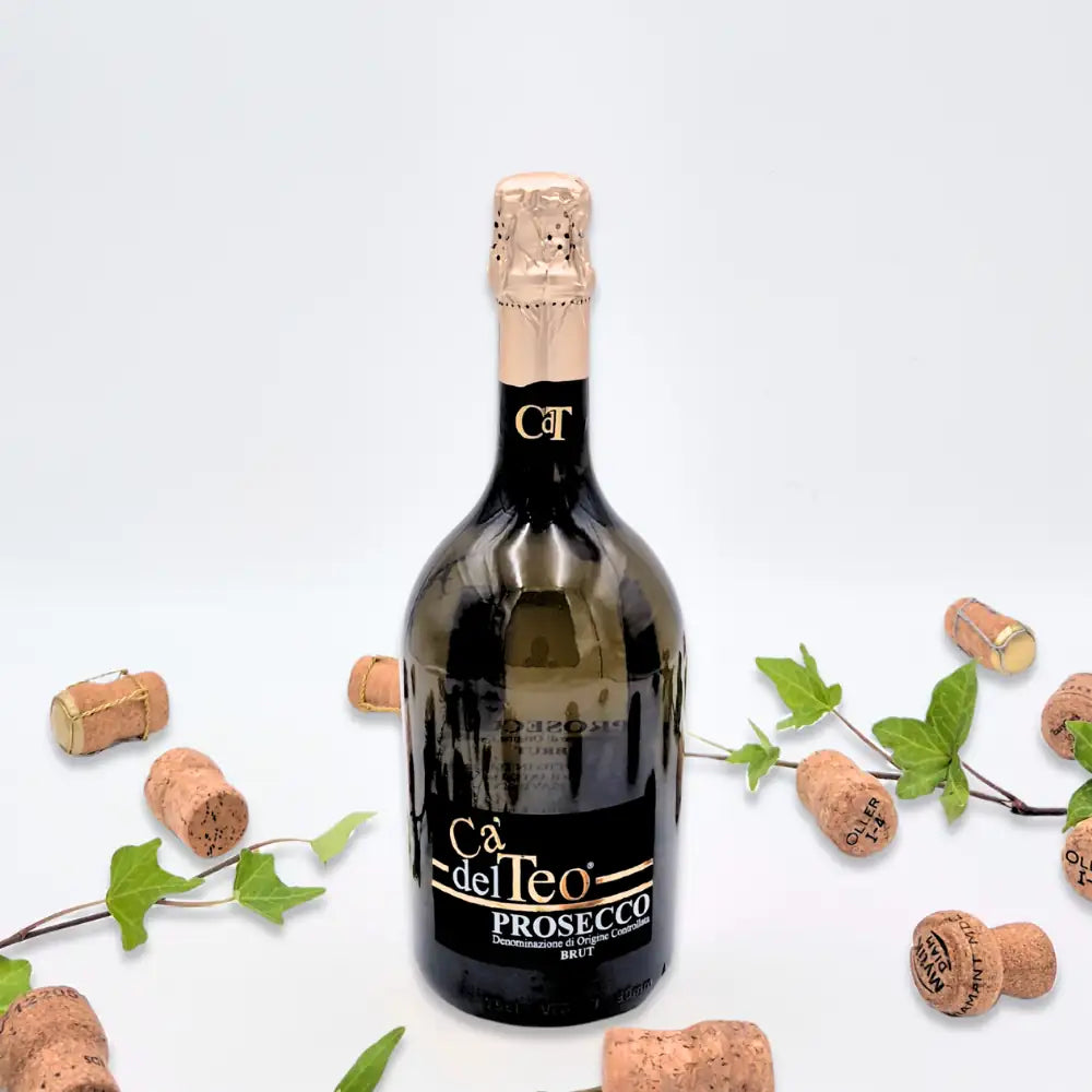 Prosecco omgivet af vinkorker, grønne blade og to hvide lysestager på hvid baggrund.
